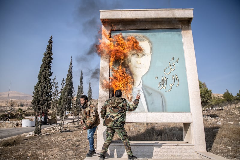 A man sets fire to a photograph of fallen Syrian dictator Bashar al-Assad at the border between Lebanon and Syria. Photograph: Sally Hayden