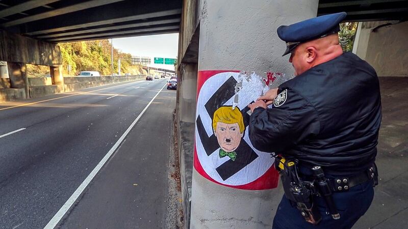 Hater or hated?: a police officer removes a depiction of Donald Trump as a Nazi from a highway bridge in Atlanta, Georgia. Photograph: John Spink/Atlanta Journal-Constitution/EPA