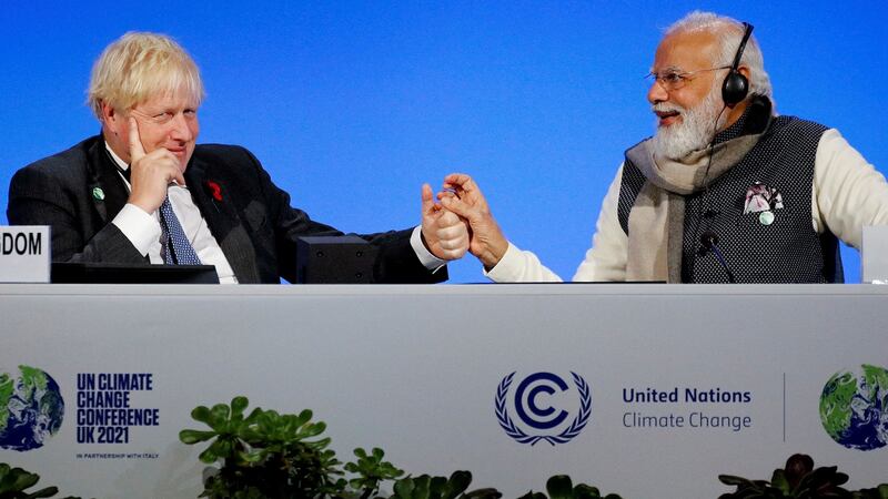 TOPSHOT - Britain's Prime Minister Boris Johnson (L) and India's Prime Minister Narendra Modi hold hands during a session on the second day of the COP26 UN Climate Summit in Glasgow on November 2, 2021. - World leaders meeting at the COP26 climate summit in Glasgow will issue a multibillion-dollar pledge to end deforestation by 2030 but that date is too distant for campaigners who want action sooner to save the planet's lungs. (Photo by PHIL NOBLE / POOL / AFP) (Photo by PHIL NOBLE/POOL/AFP via Getty Images) *** BESTPIX ***