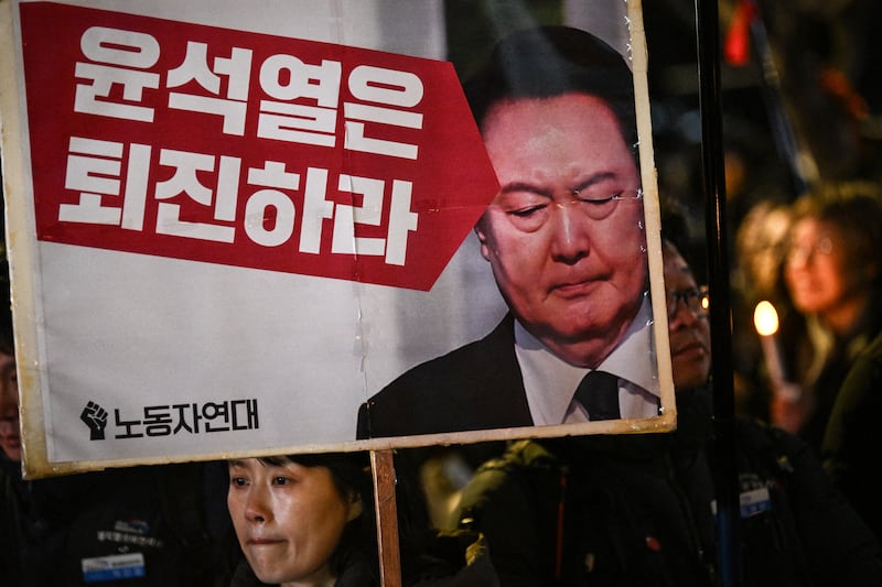 A woman holding a sign that reads 'Yoon Suk Yeol should step down' during a vigil against the South Korean president in Seoul on December 4th, 2024. Photograph: Philip Fong/AFP