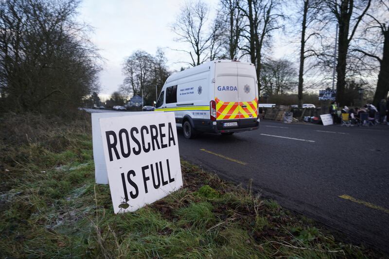 A Garda van passes protesters at the Racket Hall Hotel in Roscrea, Co Tipperary, who are demonstrating over plans to house asylum seeker family applicants. Photograph: Niall Carson/PA Wire