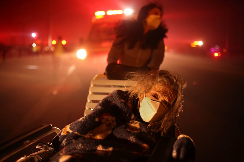 A woman is evacuated as wildfires spread through Los Angeles. Photograph: Ethan Swope/AP