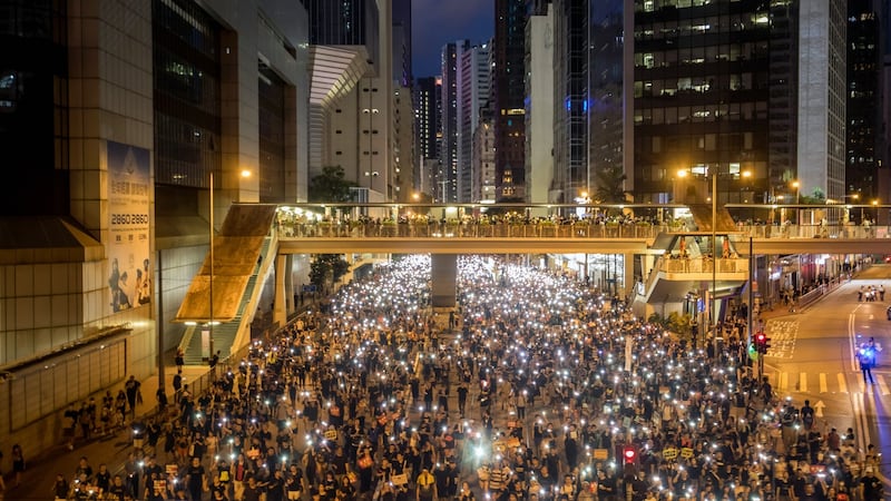 Protesters shine smartphone lights and hold placards during the annual pro-democracy rally in Hong Kong on Monday. Photographer: Paul Yeung/Bloomberg