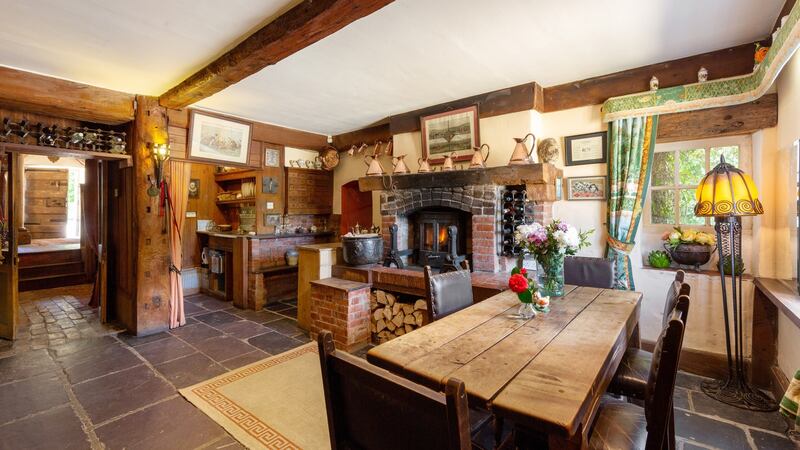 The kitchen has low-slung exposed beamed ceilings and a raised fireplace with solid-fuel burner