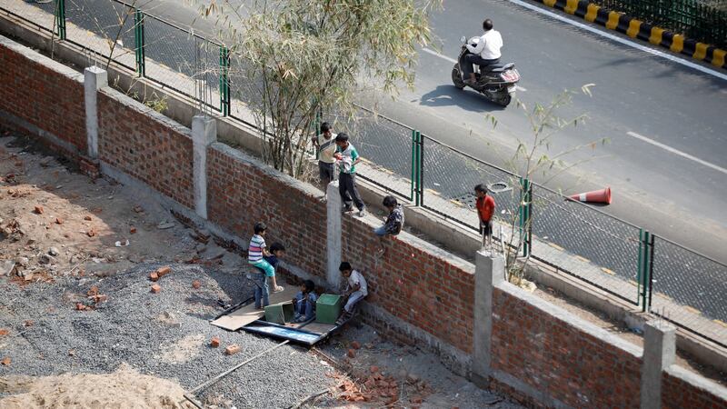 Children play on a wall that was built along a route that US president Donald Trump and India’s PM Narendra Modi will be taking, in Ahmedabad, India. Photograph: Amit Dave/Reuters