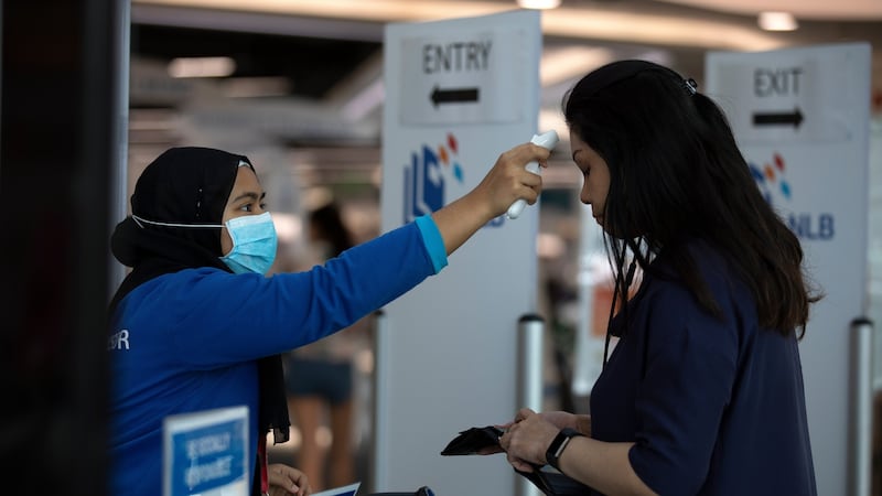 A staff takes the temperature of a visitor at the entrance of a library in Singapore. Photograph: How Hwee Young/EPA