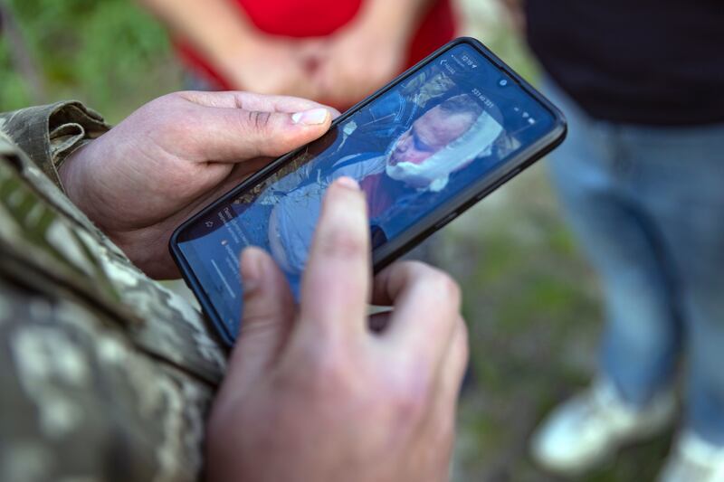 A Ukrainian soldier on May 14th, in Chernihiv, Ukraine, with a mobile phone showing a picture of the Russian pilot who was captured in March. Photograph: David Guttenfelder/The New York Times