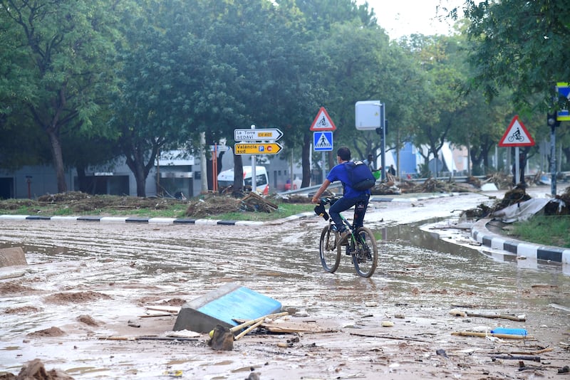 A man cycles in a street covered in mud following floods in Picuana, near Valencia, eastern Spain. Photograph: Jose Jordan / AFP via Getty Images