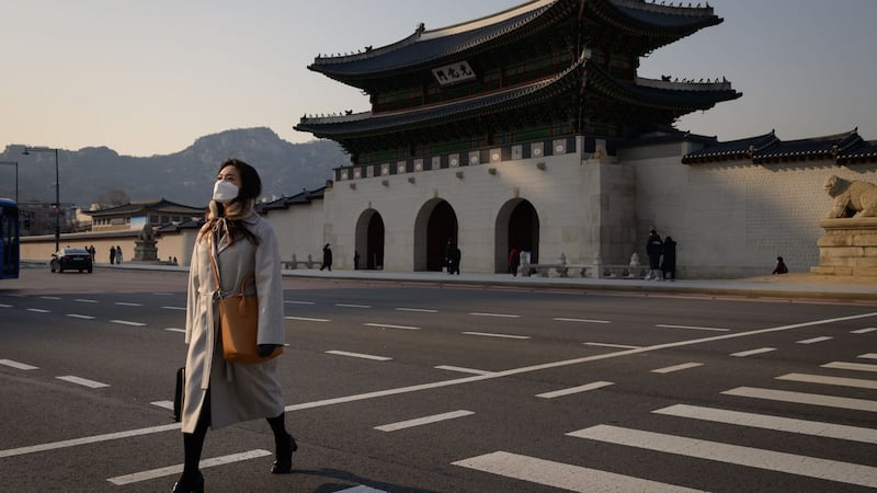 Pedestrians wearing face masks, amid concerns about the spread of the COVID-19 novel coronavirus, cross a road in front of the Gyeongbokgung palace in central Seoul on March 6, 2020. - Seoul threatened to retaliate on March 6 over what it called Tokyo's "irrational" plan to quarantine arrivals from South Korea over the coronavirus outbreak, turning the scientific issue into a diplomatic row. (Photo by Ed JONES / AFP) (Photo by ED JONES/AFP via Getty Images)