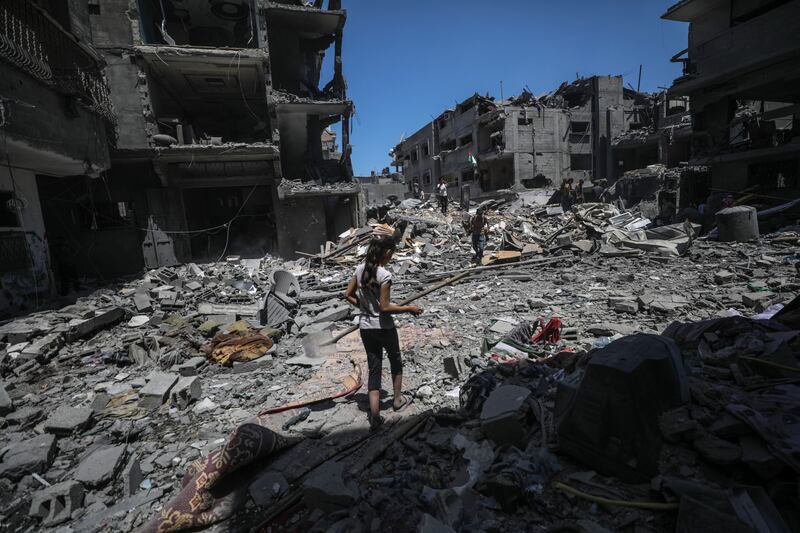 Palestinians walk among the destruction after an Israeli air strike at al-Bureij refugee camp. Photograph: Mohammed Saber/EPA