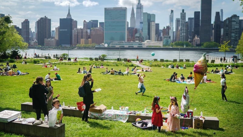 A family celebrates a child’s sixth birthday at Gantry Plaza State Park in Queens, New York, with a view of Midtown Manhattan across the East River, on Monday. Photograph:  Chang W Lee/New York Times)