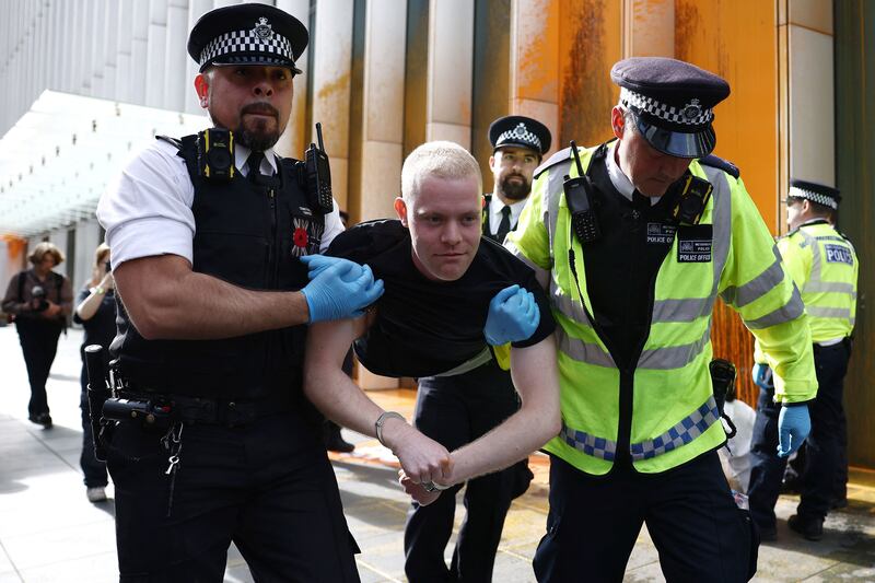 A Just Stop Oil climate activist is detained after activists threw orange paint at the UK headquarters of TotalEnergies in the Canary Wharf district in London on Tuesday to protest against the construction of the East African Crude Oil Pipeline. Photograph: Henry Nicholls/AFP/Getty Images