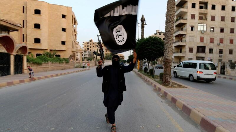 A member loyal to Isis waves a flag of allegiance to the militant group, in Raqqa. Photograph: Reuters