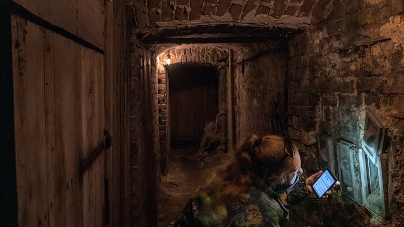 Natalia Kovtun uses the flashlight on her smartphone to check a cubbyhole in her apartment building’s basement bomb shelter in Lviv, Ukraine. Kovtun says she is worried about a saboteur planting a bomb in the shelter.  Photograph: Mauricio Lima/The New York Times