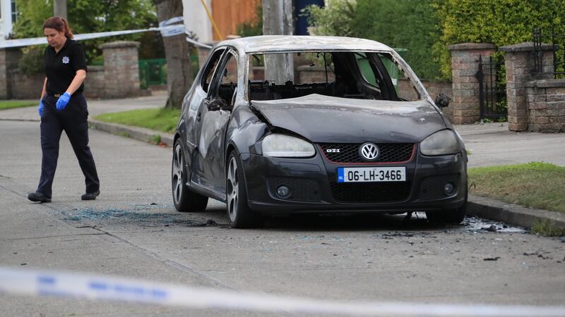 Gardaí examine the burned out suspected getaway car on Santry Close. Photograph: Collins.