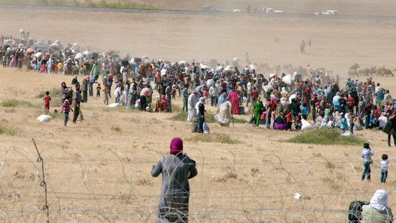 Syrian Kurds wait behind the border fence to cross into Turkey near the southeastern town of Suruc in Sanliurfa province. Photograph: Reuters