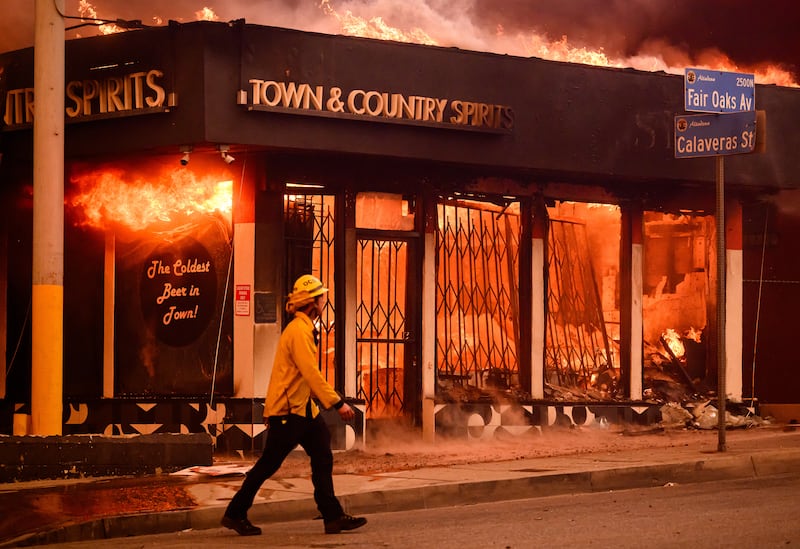 A firefighter walks past the same burning liquor store. Photograph: Josh Edelson/AFP