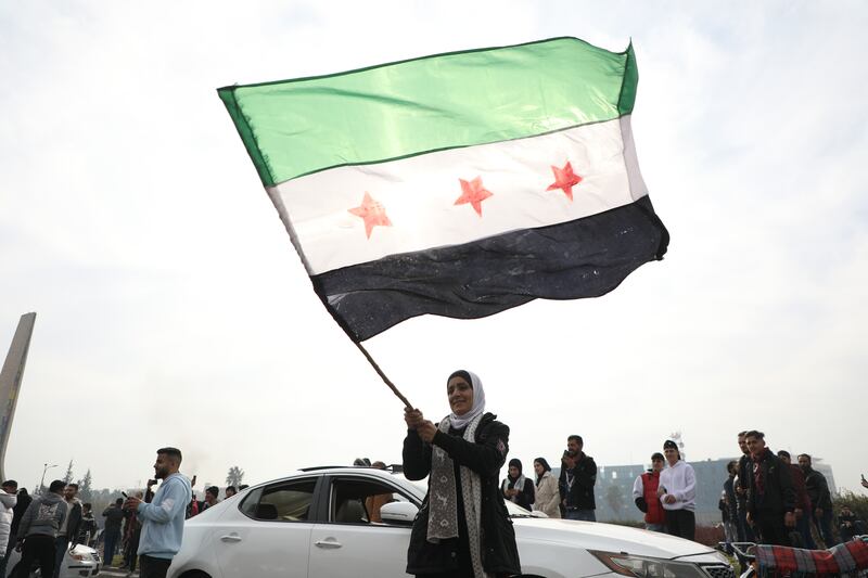  A woman waves the flag of the Syrian rebels as people gather to celebrate the fall of the government, in Umayyad Square  in Damascus. Photograph: Ali Haj Suleiman/Getty Images