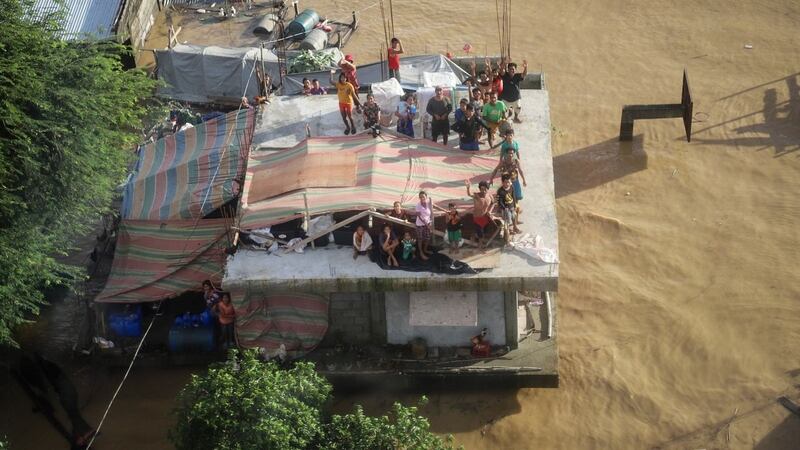 A handout photo made available by the Philippine Coast Guard shows residents on top of houses submerged in water following the aftermath of typhoon Vamco in Cagayan region, northern Luzon, Philippines, Saturday. Photograph: Philippine Coast Guard