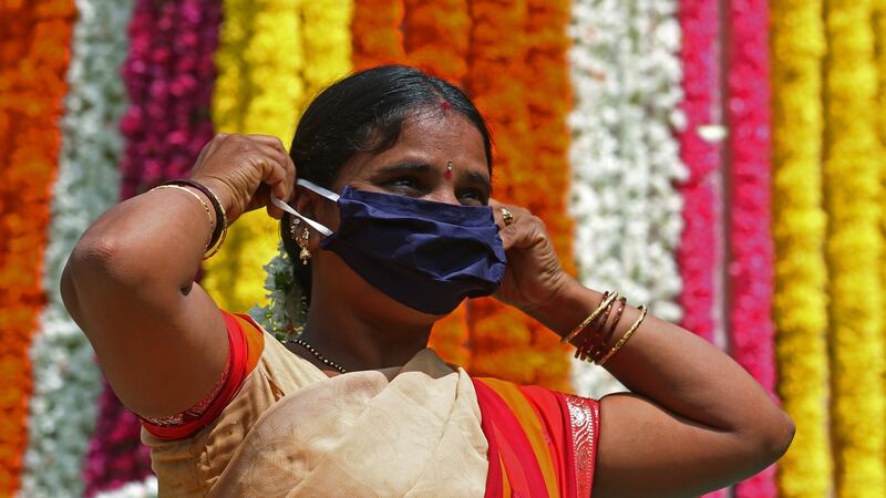 An Indian woman wears a face mask and walks in front of a statue of Mahatma Gandhi in Bangalore, India. Photograph: Jagadeesh/EPA