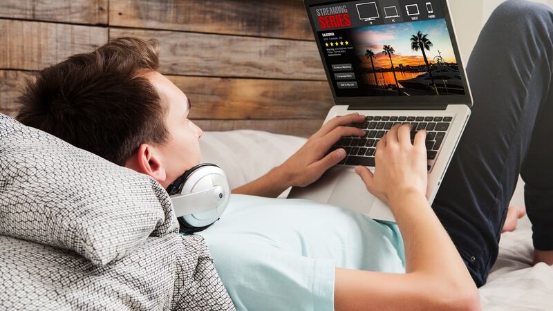 Man watching streaming series in a laptop computer, lying in the bed. Photograph: AFP/Getty Images