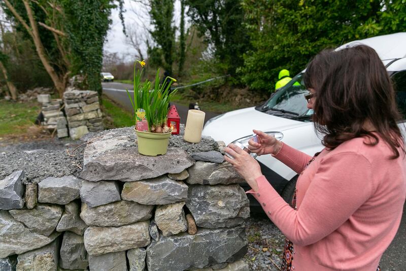 A woman lights a candle at the entrance to Menlo Pier in Galway where three men lost their lives after the car they were in entered the water. Photograph: Andy Newman