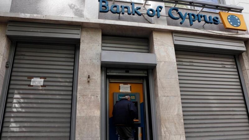 A man makes a transaction at an ATM  outside a branch of Bank of Cyprus in Athens, Greece today. Greek branches of Cypriot banks will remain shut on Tuesday and Wednesday, in line with Nicosia's plan for a bank holiday over the two days. REUTERS/John Kolesidis