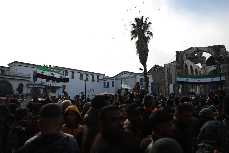 Syrians wave the independence-era flag after Friday prayers at the Umayyad mosque in Damascus on Friday. Photograph: Omar Haj Kadour/AFP via Getty