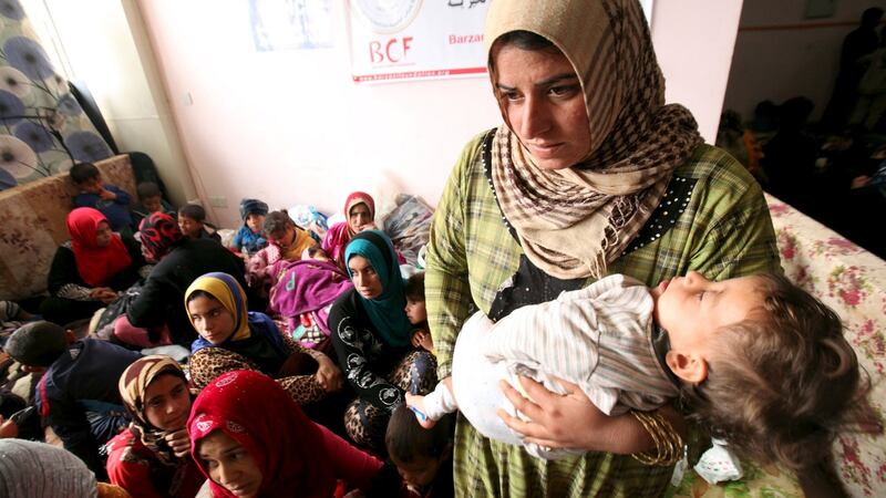 A displaced woman carries her child in a building that is used as a temporary shelter in the Makhmour area. Photograph: Azad Lashkari/Reuters