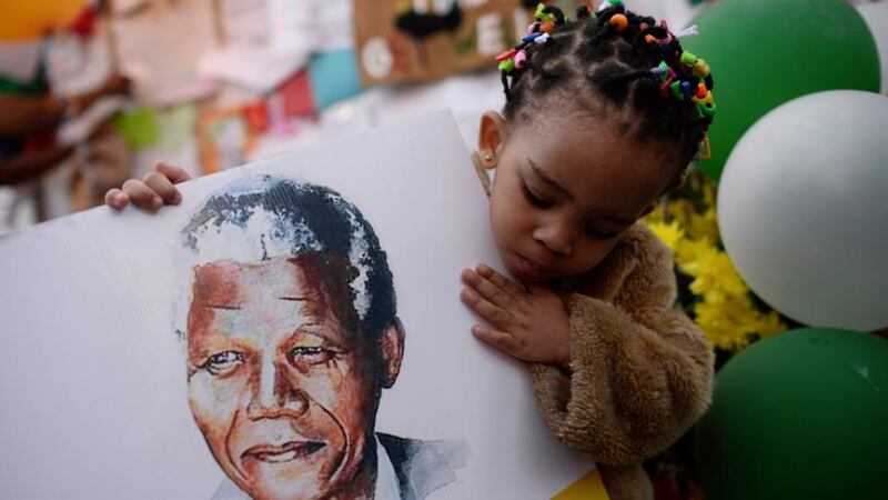 Two-year-old Precious Mali holds a picture of former South African President Nelson Mandela as well-wishers gather outside the Medi-Clinic Heart Hospital. Photograph: Dylan Martinez/Reuters