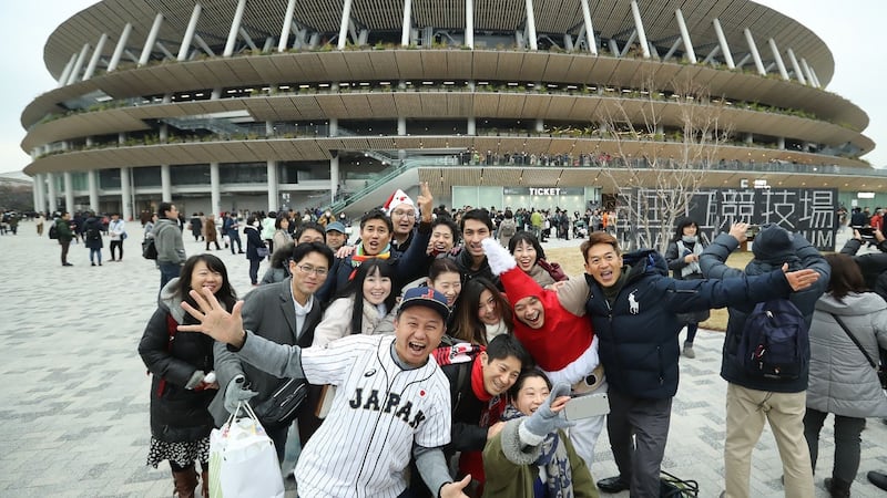 People pose  outside the new National Stadium in Tokyo on Saturday December 21st. The stadium is the main venue for the upcoming Tokyo 2020 Olympic Games in July. Photograph: STR/Jiji Press/AFP via Getty Images