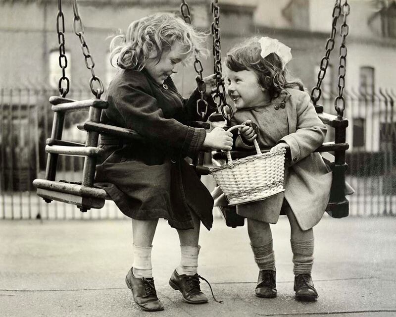 Photograph by Stanley Matchett: Two little girls on swings near Clifton Street in Belfast in the 1960s. At that time, none of us could have imagined how much life in the city would change over the next decades