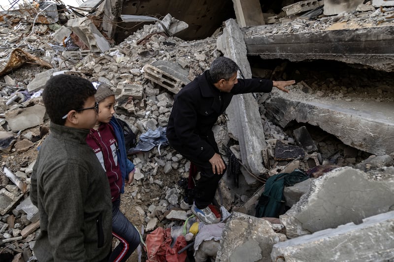 With his children at his side, Hani al-Dibs explains how he crawled through a gap and was able to recover parts of a skeleton that he believes belonged to his eight-year-old son Hasib, at his family’s destroyed home in Jabaliya, northern Gaza Strip. Photograph:   (Saher Alghorra/New York Times
                      