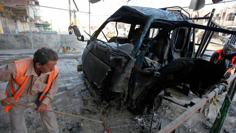 Workers clean up the site of a car bomb attack in Baghdad. Photograph: Thaier al-Sudani/Reuters