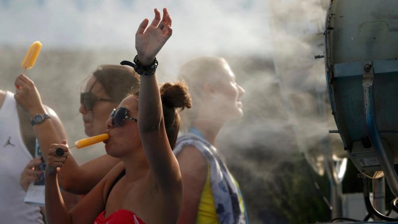 Spectators cool off with ice pops  in front of a misting fan at the Australian Open  in Melbourne, where temperatures were again over 40 degrees Celsius. Photograph:  Jason Reed. Photograph: Reuters