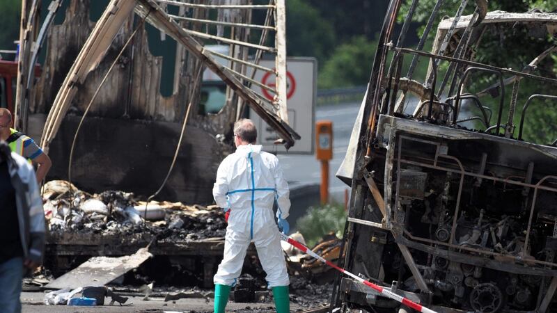 A forensic expert works at the scene where a tour bus burst into flames following a collision with a trailer truck on the highway A9 near Münchberg, southern Germany. Photograph:  Nicolas Armer AFP/Getty Images