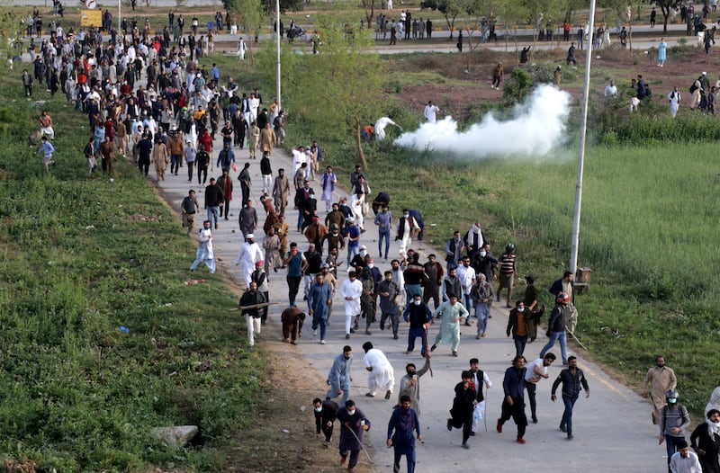 Supporters of opposition party Pakistan Tehrik-e-Insaf run from tear gas during clashes with police. Photograph: Sohail Shahzad/EPA