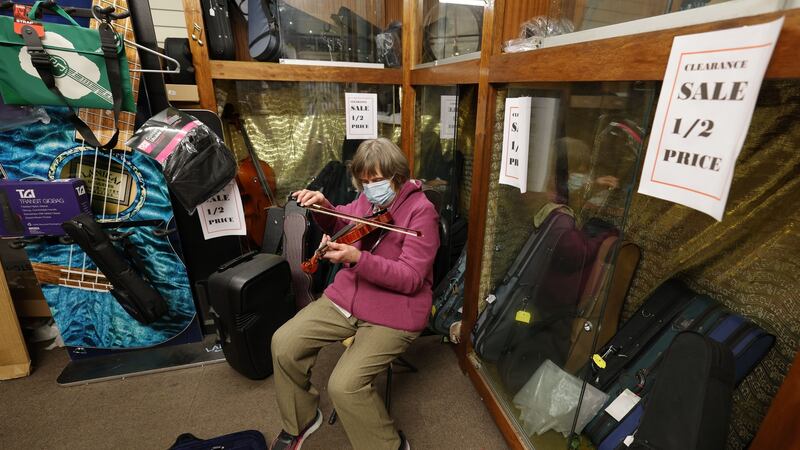 Maria Byrne  plays a violin while waiting for the last customers at Charlie Byrne’s music shop. Photograph: Alan Betson