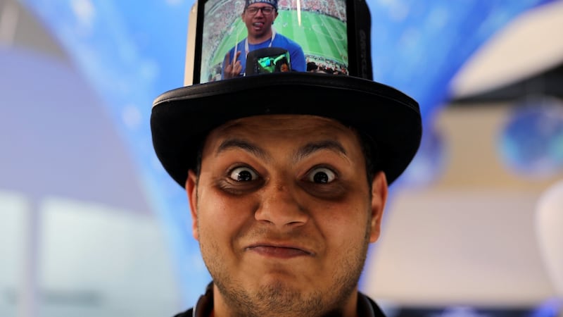 A visitor poses while wearing a hat packed with a Flexible+ display by the Chinese company Royole. Photograph: Reuters