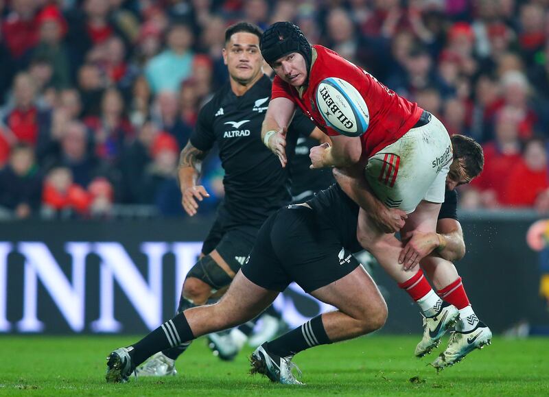 Munster's Rory Scannell offloads while tackled during the clash against New Zealand XV at Thomond Park. Photograph: Ken Sutton/Inpho
