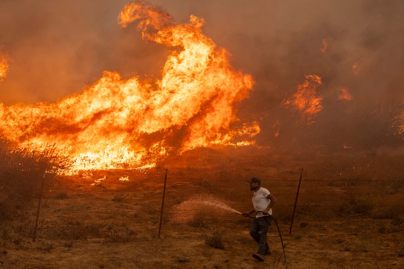 Jaime Hernandez sprays water to defend his home from approaching flames. Photograph: Stephen Lam/San Francisco Chronicle via AP