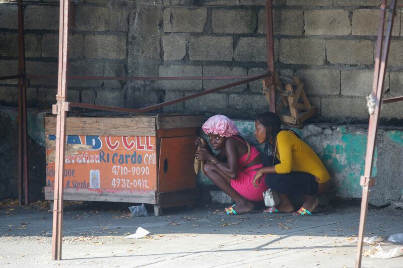 Women take cover during a gun battle between police and gang members in Haiti. Photograph: Odelyn Joseph/AP