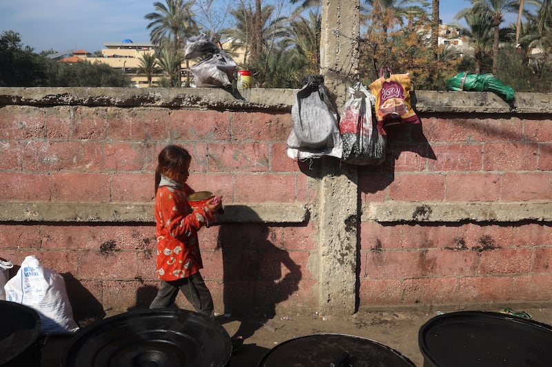 A Palestinian girl with food she collected at a distribution point in Deir al-Balah in the central Gaza Strip on Friday. Photograph: Eyad Baba/AFP via Getty Images