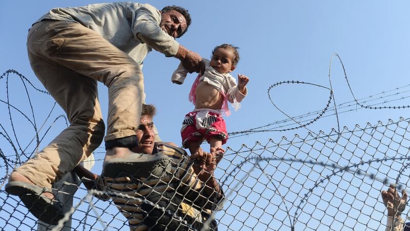 A Syrian child is lifted over a border fence into Turkish territory in June. Photograph: Bulent Kilic/AFP/Getty