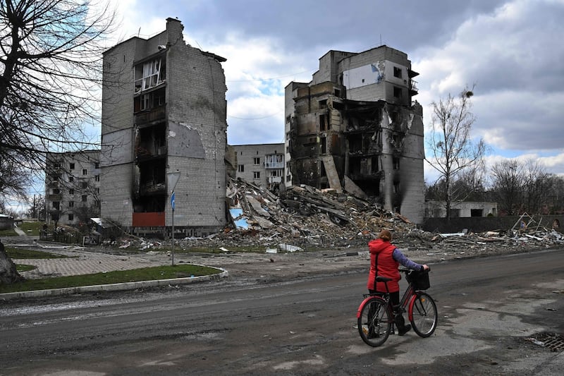 A woman carries her bicycle past destroyed buildings in the town of Borodianka, northwest of Kyiv, on April 4th, 2022. Photograph: Photo by Sergei SUPINSKY / AFP via Getty Images