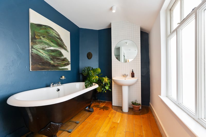 The family bathroom has timber floors, an antique roll-top bathtub with clawed feet and a step-in shower unit. 