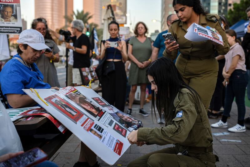 An Israeli soldier tapes a photo of her friend Ron Sherman, who is among the 203 people believed have been kidnapped by Hamas militants, to a poster during a demonstration in Tel Aviv, Israel, on Friday. Photograph: Tamir Kalifa/The New York Times 