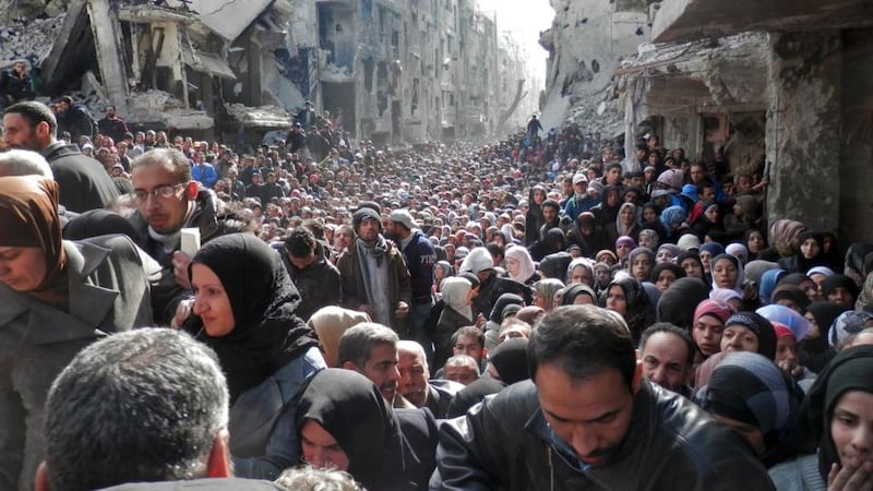 In this handout provided by the United Nation Relief and Works Agency (UNRWA), residents wait in line to receive food aid in the Yarmouk refugee camp. Photograph: UNRWA via Getty 