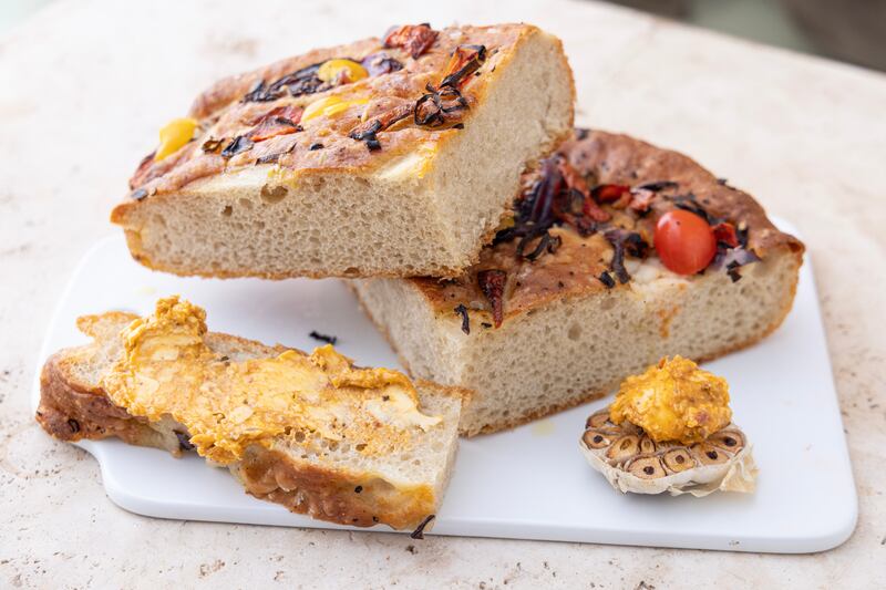 Tomato, rosemary, and red onion focaccia with whipped roasted garlic and tomato butter. Photograph: Harry Weir