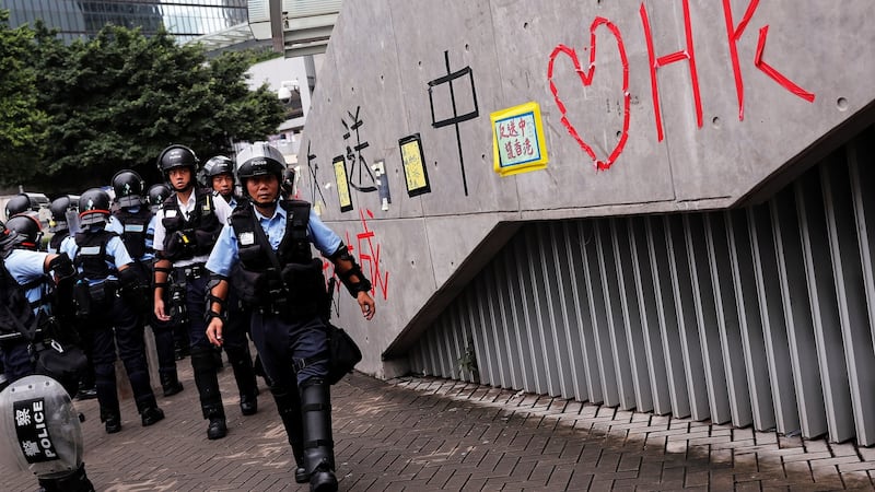 Riot police officers walk past a wall covered with messages written by supporters of pro-democracy protesters. Photograph: Tyrone Siu/Reuters